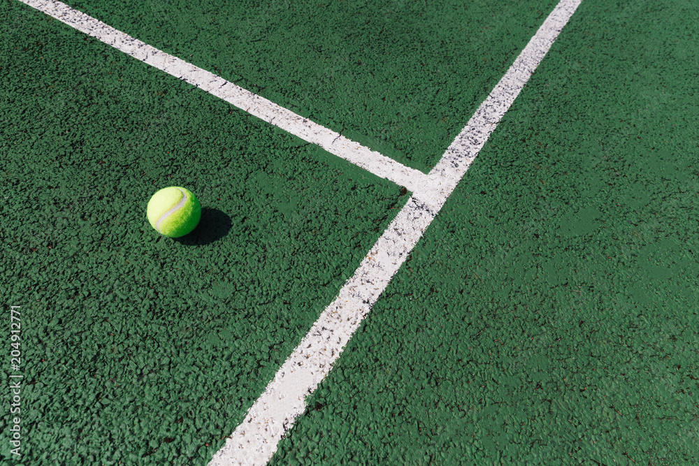 Yellow tennis ball on green tennis court