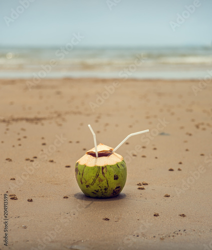 Coconut with a straw on the ocean. Tropical fruits.