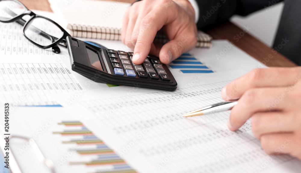 Businessman working with using a calculator to calculate the numbers. Finance accounting concept Businessman working with using a calculator to calculate the numbers. Finance accounting concept