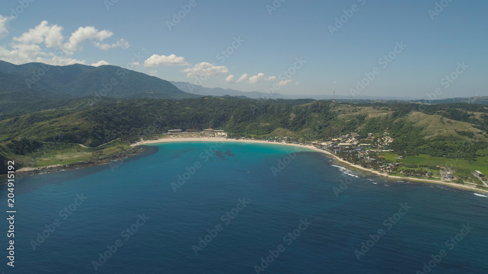 Aerial view of beautiful tropical beach with turquoise water in blue lagoon, Pagudpud, Philippines. Ocean coastline with sandy beach. Tropical landscape in Asia.