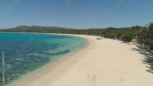 Aerial view of beautiful tropical beach Saud with turquoise water in blue lagoon  Pagudpud  Philippines. Ocean coastline with sandy beach and palm trees. Tropical landscape in Asia.