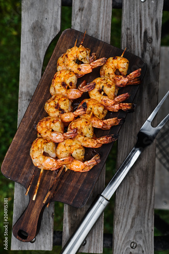 High angle view of plate of grilled shrimp on skewers cooling by the side of the barbecue