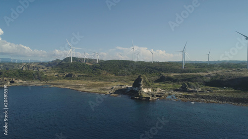 Natural rock formation of limestone stone on the coast with windmills for electric power production. Aerial view of tourist attraction Kapurpurawan Rock Formation in Ilocos Norte Philippines,Luzon. photo