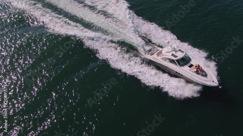 Wallpaper Mural Drone shot of yacht sailing in the ocean waters with people sitting in front deck. Group of men and women relaxing on private yacht deck. Torontodigital.ca