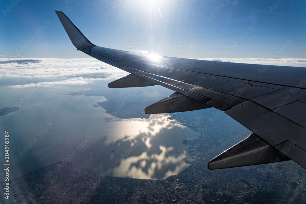 Obraz premium View through the window of the wing of an airplane flying above the clouds