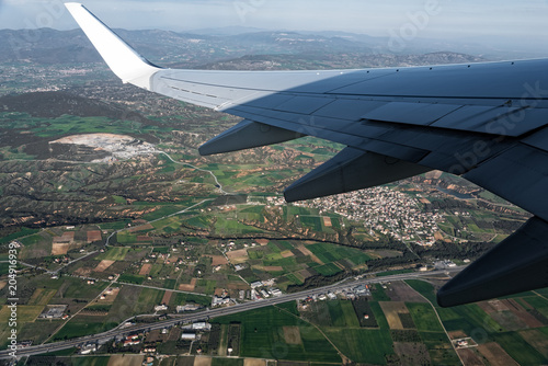 View through the window of the wing of an airplane flying above the countryside