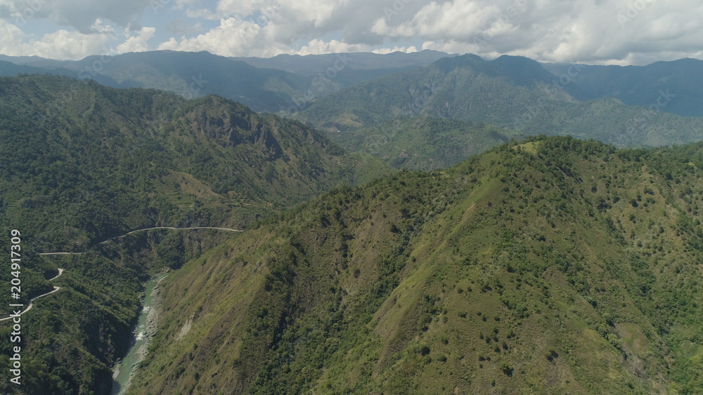 Obraz premium Aerial view of mountain river in the cordillera, road on the slopes, mountains covered forest, trees. Cordillera region. Luzon, Philippines. Mountain landscape sky with clouds.