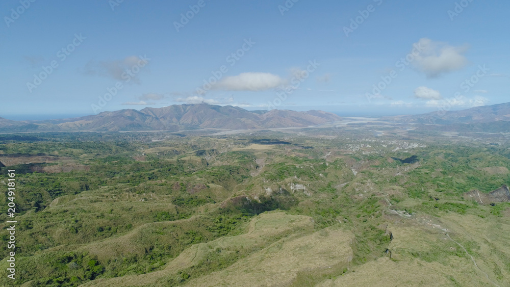 Aerial view of mountains covered with green vegetation, valley, trees in vicinity volcano Pinatubo. Slopes of mountains, sky and clouds. Cordillera region. Luzon, Philippines. Aerial view of mountains covered with green vegetation, valley, trees in vicinity volcano Pinatubo. Slopes of mountains, sky and clouds. Cordillera region. Luzon, Philippines.