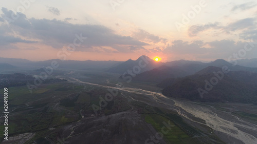 Aerial view sunset in mountain valley along which the river flows, surrounded by mountains covered with forest. Pinatubo, Cordillera region. Luzon, Philippines. Mountain landscape. photo