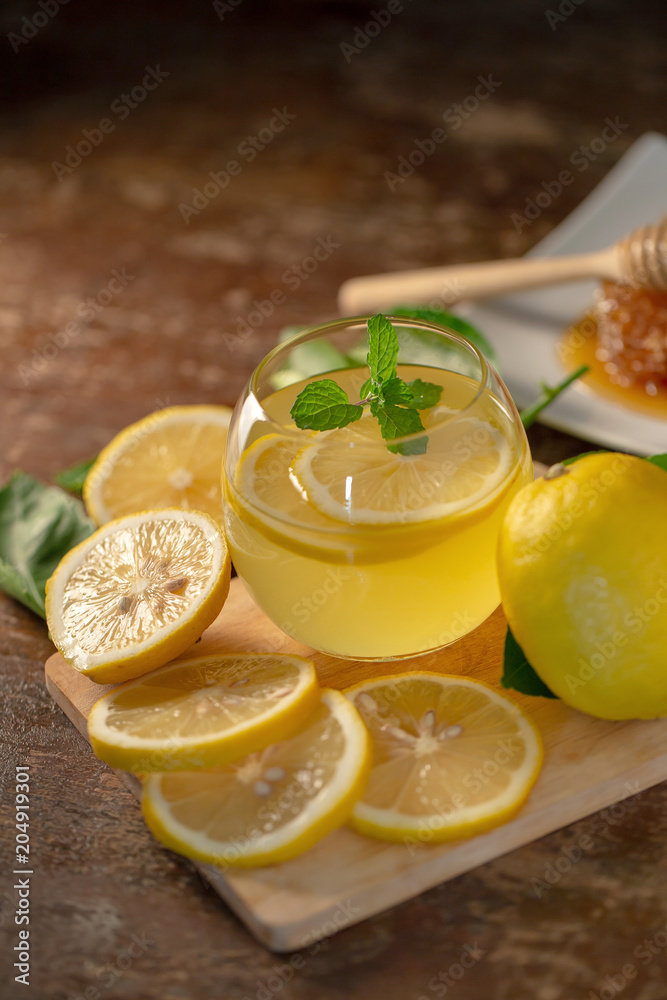 Lemon juice with honey on wooden table, lemons and sage leaves Lemon juice with honey on wooden table, lemons and sage leaves