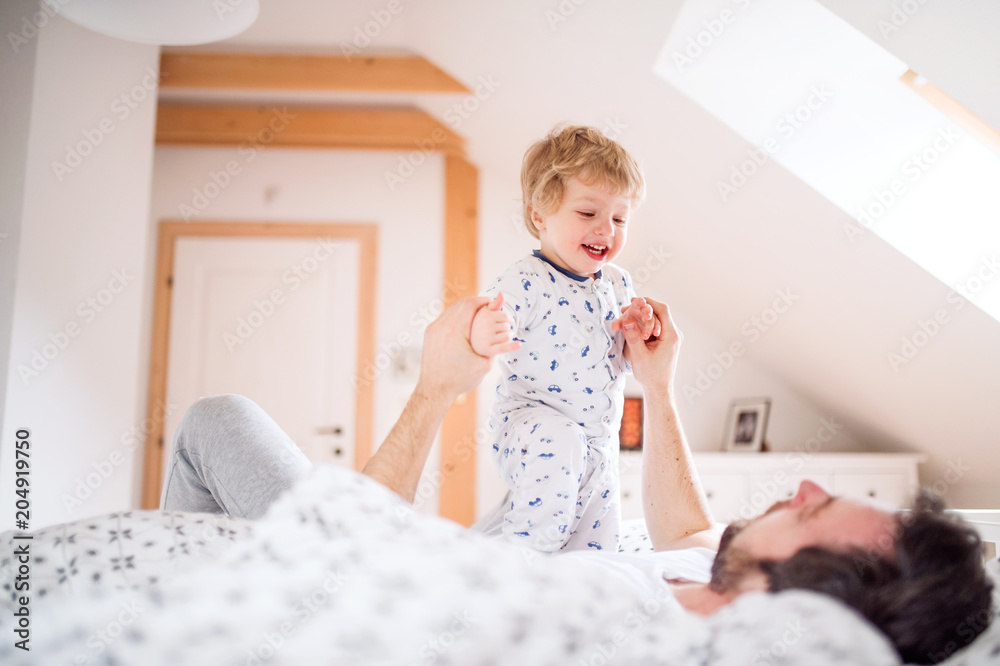 Father with a toddler boy having fun in bedroom at home at bedtime. Father with a toddler boy having fun in bedroom at home at bedtime.