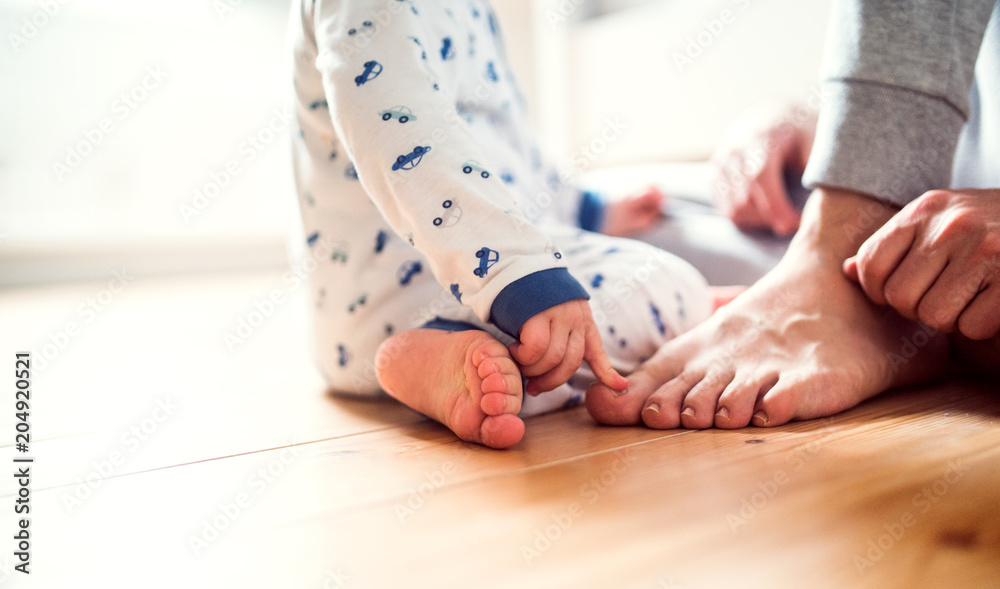 Father with a toddler boy sitting on the floor in bedroom at home. Father with a toddler boy sitting on the floor in bedroom at home.