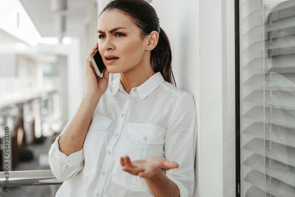 Portrait of upset businesswoman solving issues by phone. She is speaking and gesturing Portrait of upset businesswoman solving issues by phone. She is speaking and gesturing
