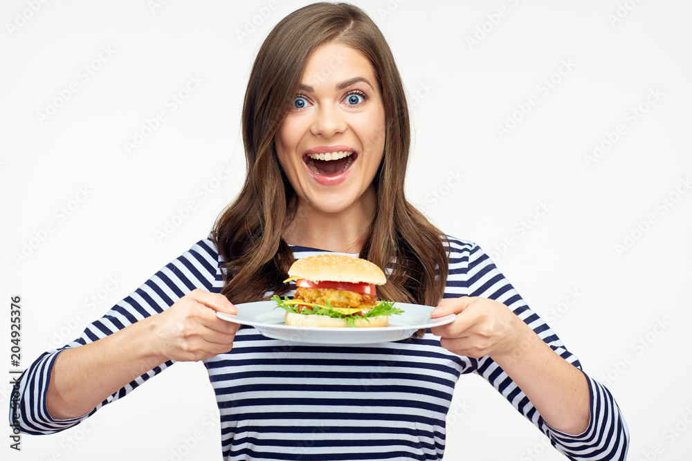 Happy emotional woman holding burger on white plate.