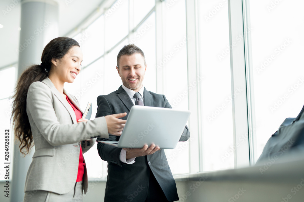 Waist up portrait of cheerful modern businesswoman talking to partner discussing work and holding laptop, copy space