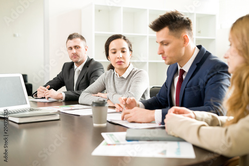 Portrait of business people sitting in row at meeting table in conference room discussing work and planning strategy