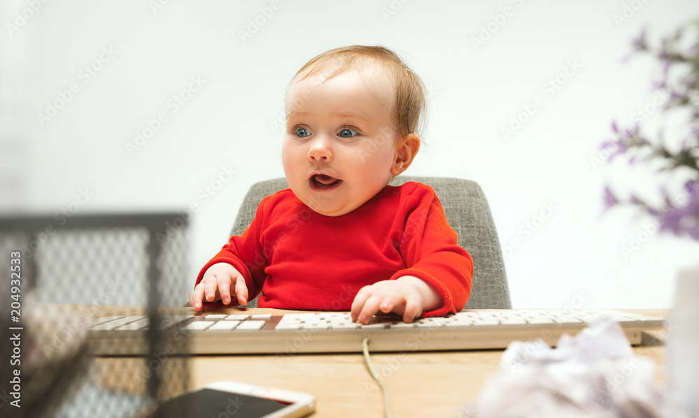 Happy child baby girl toddler sitting with keyboard of computer isolated on a white background Happy child baby girl toddler sitting with keyboard of computer isolated on a white background