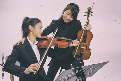 The violin teacher is teaching the violin student,put hands to student shoulder for the encourage together,violin class,at studio music room.