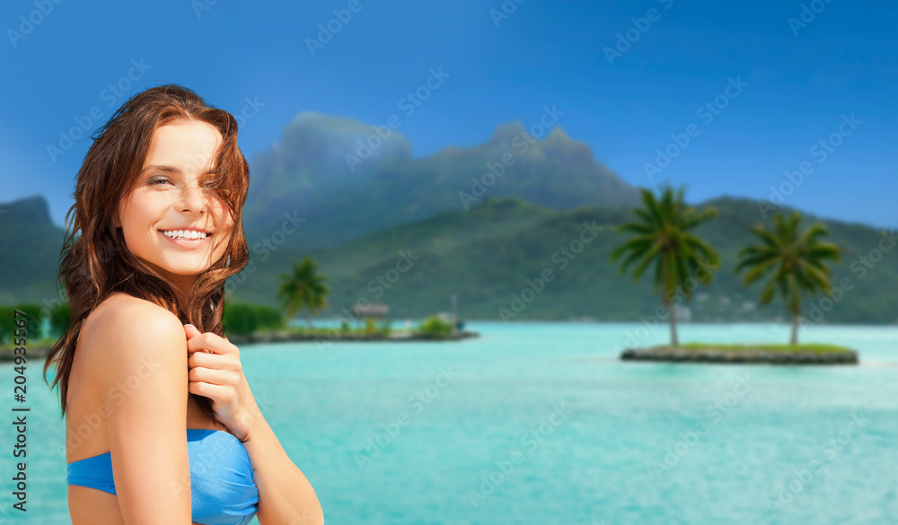 travel, tourism, summer holidays and vacation concept - happy young woman posing in bikini swimsuit at touristic resort over bora bora island beach background