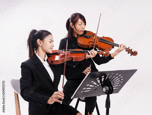 The violin teacher is teaching the violin student,the lady in front of and sitting on chair play violin,the lady at the back play viola,at studio music room,violin class