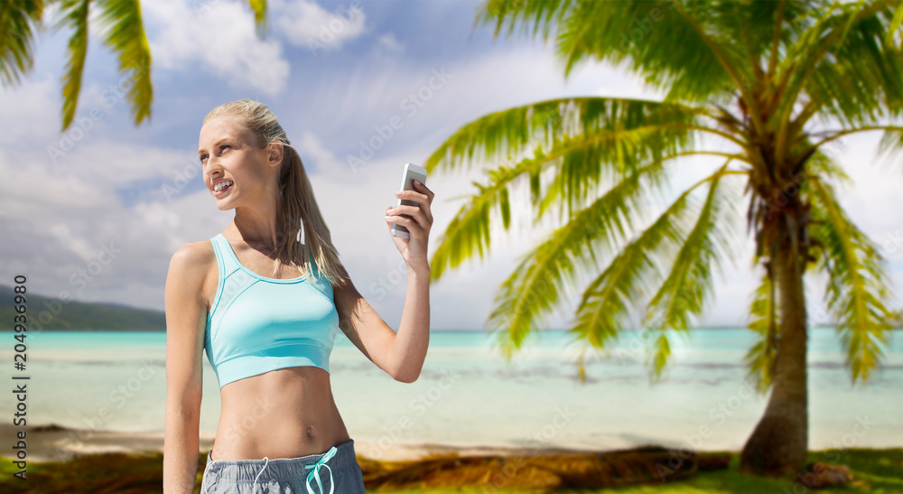 fitness, sport and technology concept - smiling young woman with smartphone over tropical beach background in french polynesia