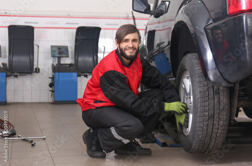 Professional mechanic changing tire in car service center