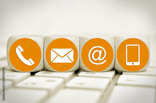 Website and Internet contact us page concept with orange icons on cubes on a keyboard
