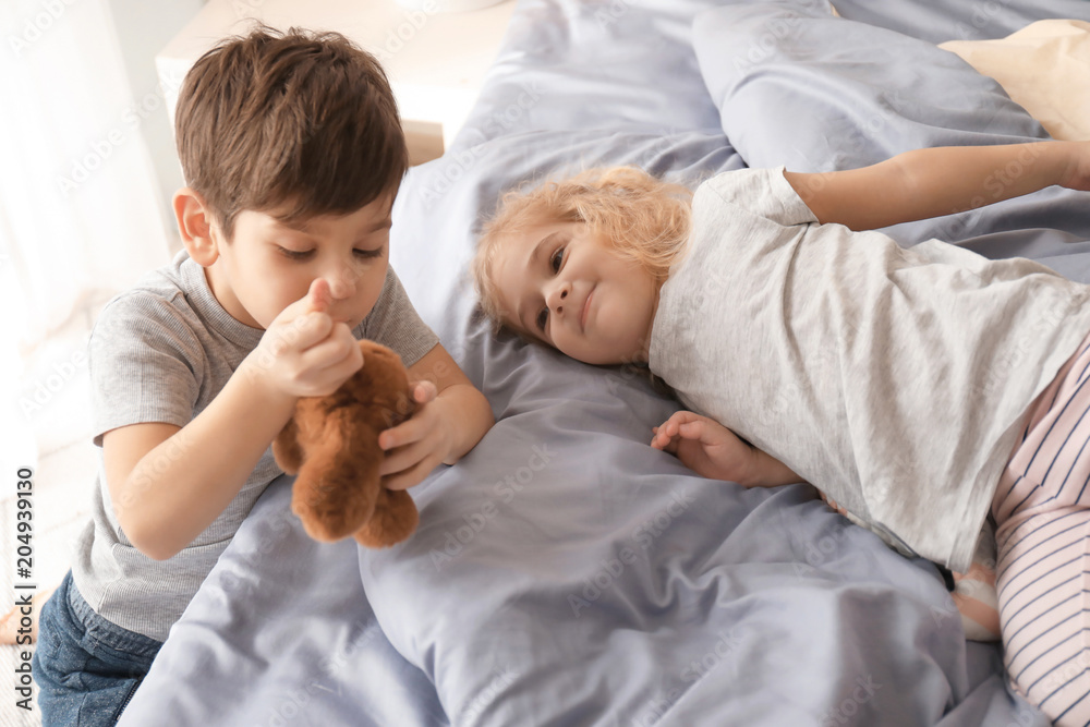 Cute children with toy on bed at home