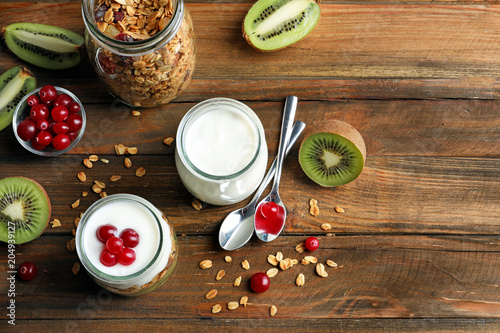 Tasty breakfast with yogurt and granola on wooden table