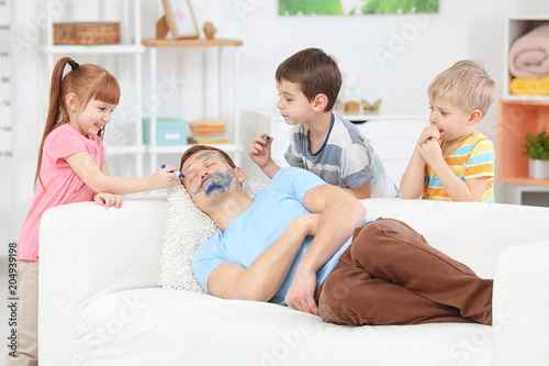 Little children painting their father's face while he sleeping. April fool's day prank