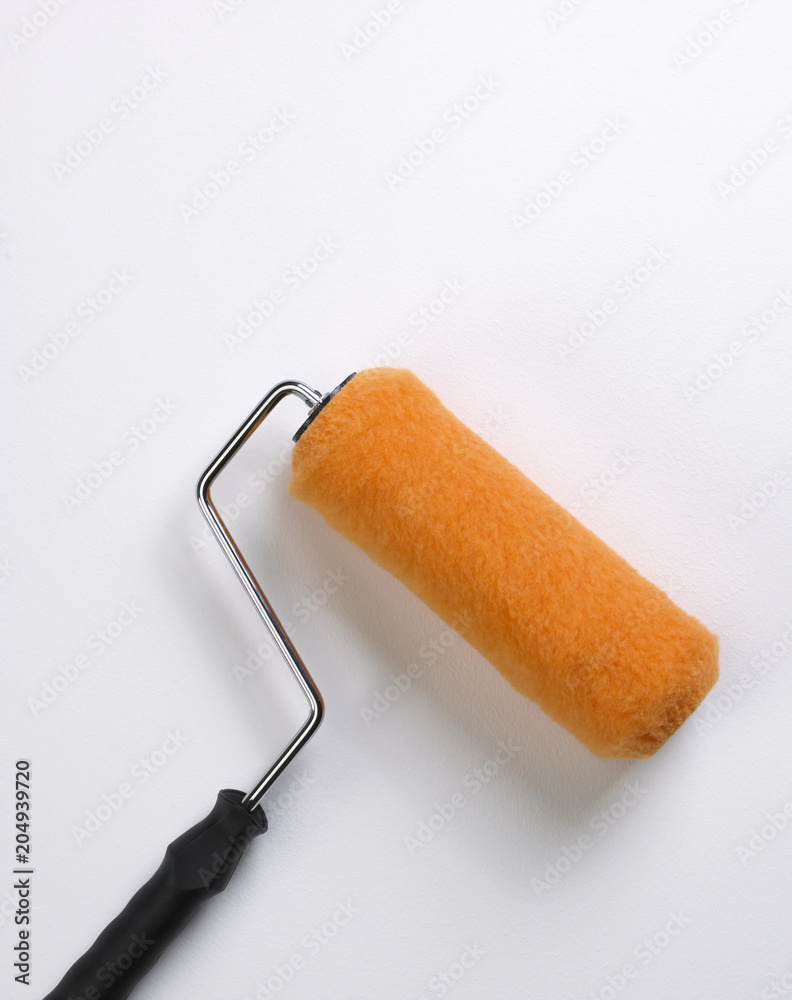 Obraz premium BRIGHT ORANGE PAINT ROLLER ON WHITE SURFACE