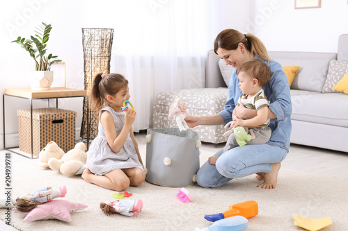 Housewife and children picking up toys after playing at home photo