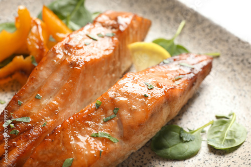 Tasty cooked salmon with lemon on plate, closeup