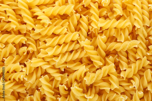 Uncooked fusilli pasta as background, closeup photo