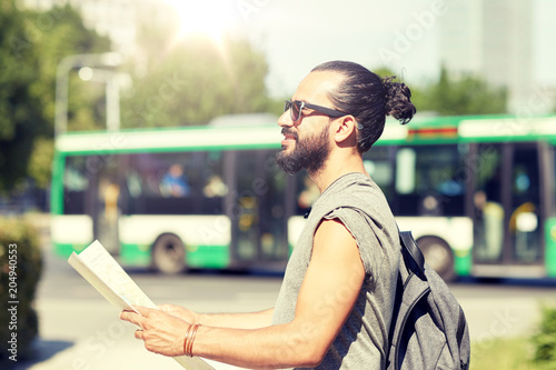 travel, tourism, backpacking and people concept - man traveling with backpack and map in city searching location photo