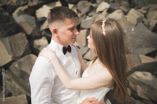 Gorgeous bride, groom kissing and hugging near the cliffs with stunning views © olegparylyak