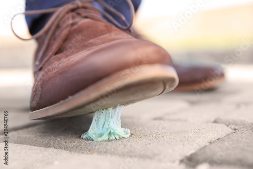 Fotografie Man stepping in chewing gum on sidewalk. Concept of stickiness
