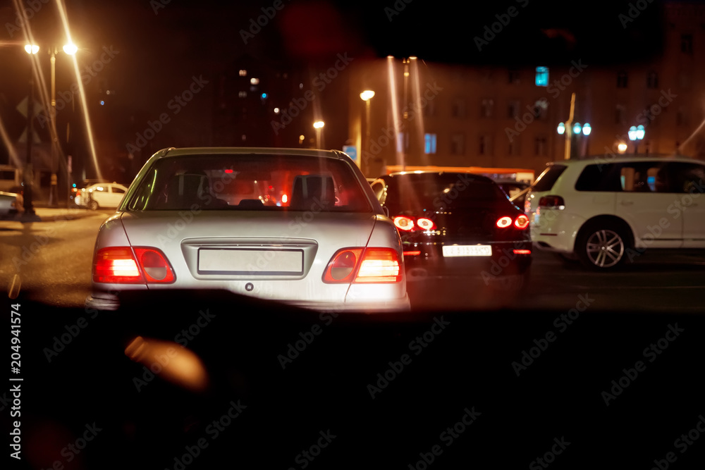 Night view of the cars. the road in the city at the night with yellow and red electrical light for cars during they are coming home. Rear view of the car at night . Back view of the car at night . Night view of the cars. the road in the city at the night with yellow and red electrical light for cars during they are coming home. Rear view of the car at night . Back view of the car at night .