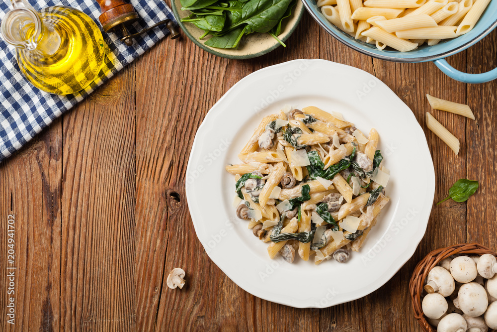 Penne pasta with spinach and mushrooms. Sprinkled with cheese. Penne pasta with spinach and mushrooms. Sprinkled with cheese.