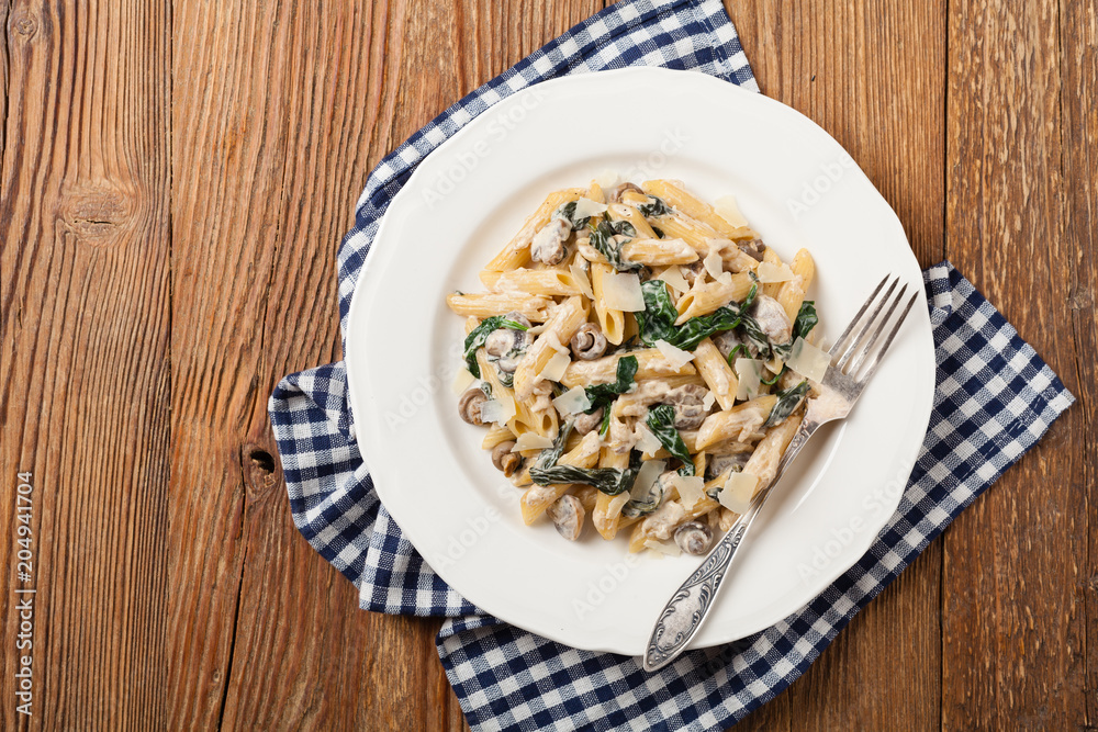 Penne pasta with spinach and mushrooms. Sprinkled with cheese. Penne pasta with spinach and mushrooms. Sprinkled with cheese.