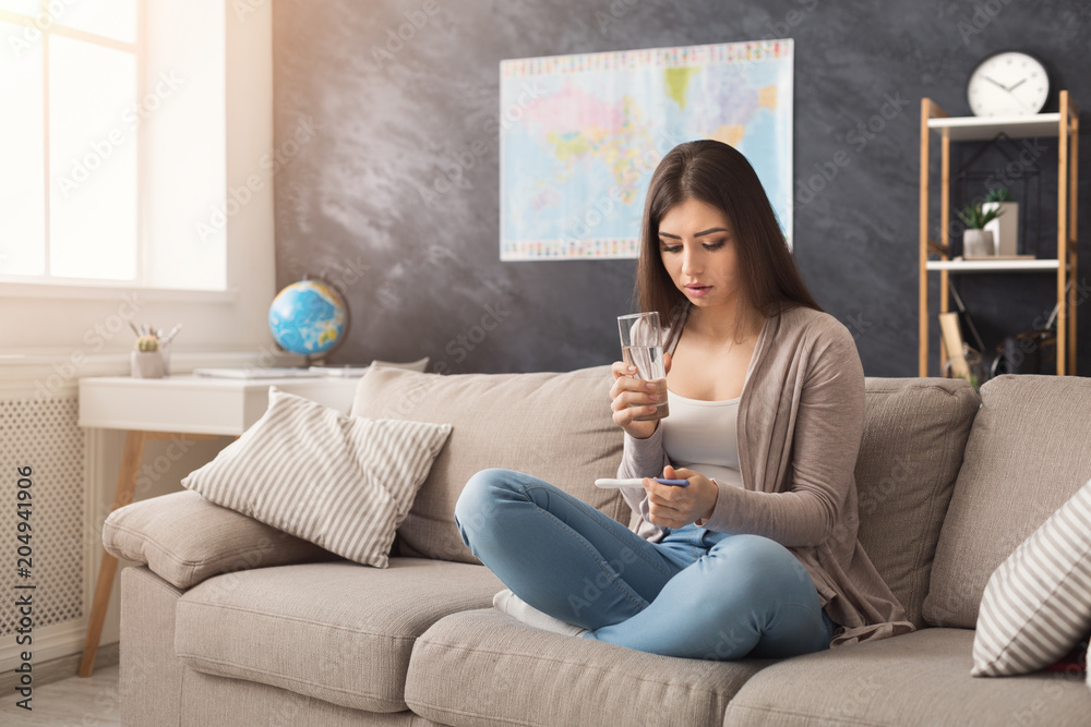 Obraz premium Sad girl reading the results of her pregnancy test