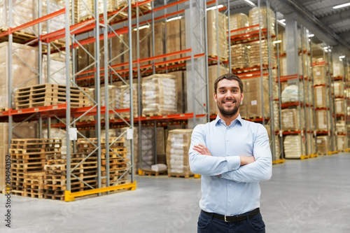 logistic business, shipment and people concept - happy businessman at warehouse