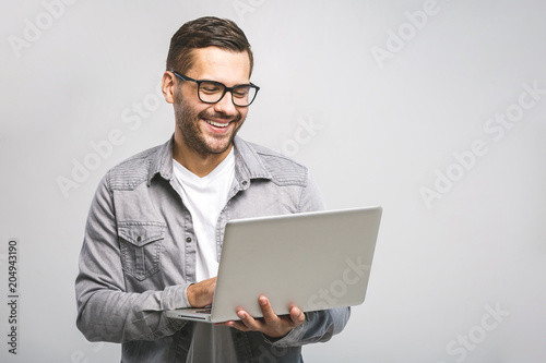 Confident business expert. Confident young handsome man in shirt holding laptop and smiling while standing against white background