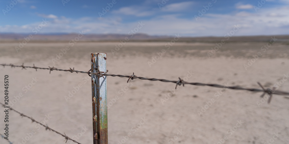 Barb wire fence in the dry desert country with metal post Barb wire fence in the dry desert country with metal post