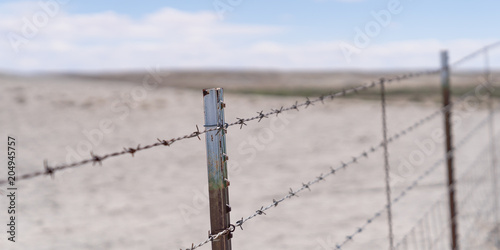 Barb wire fence in the dry desert country with metal post