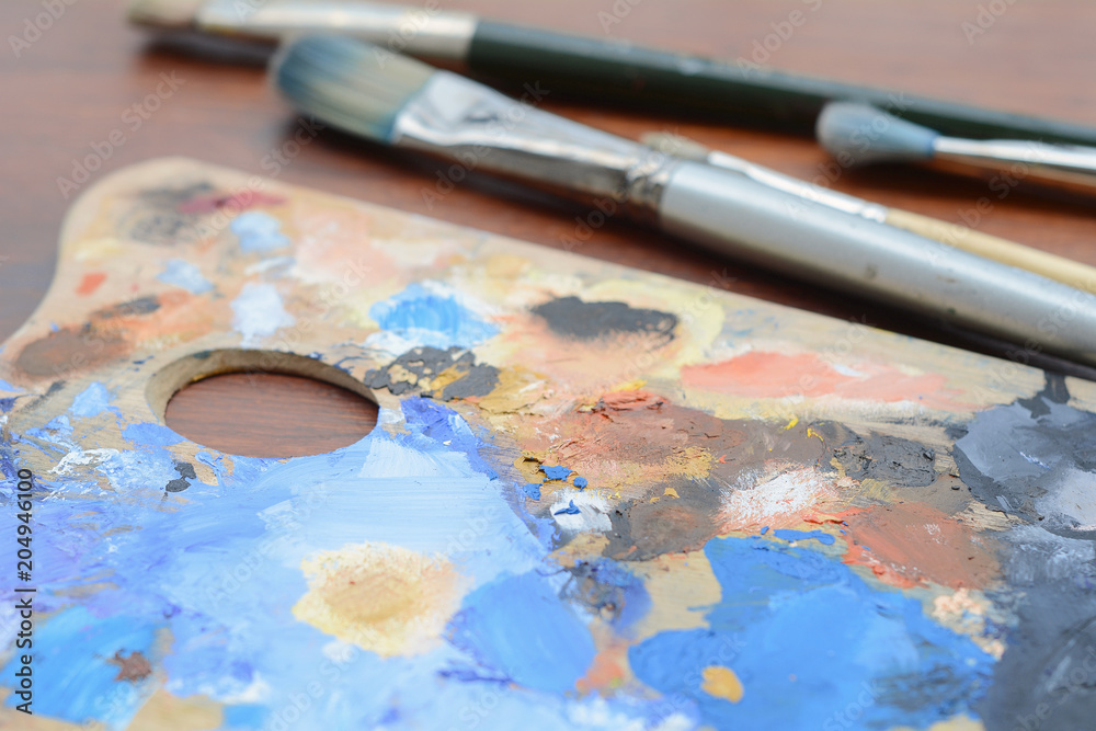 Artist's palette with colorful oil paint strokes and paintbrushes Artist's palette with colorful oil paint strokes and paintbrushes