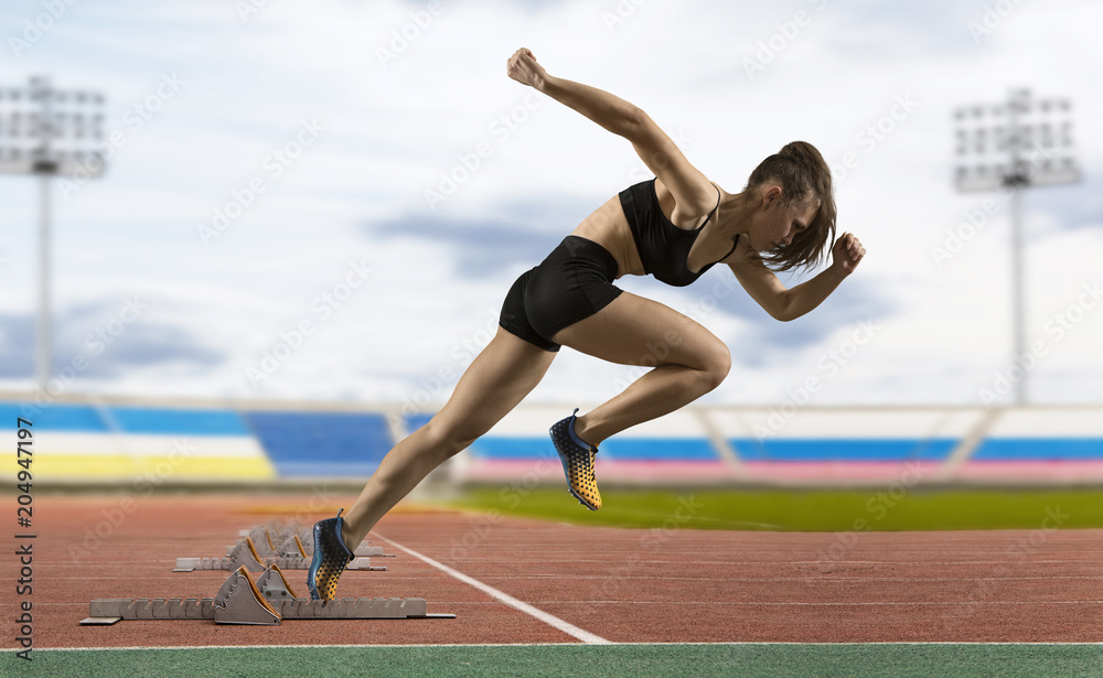 Woman sprinter leaving starting blocks on the athletic track