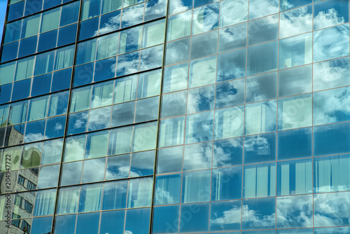 Modern industrial building with glass. Reflection of blue sky with clouds in the windows.