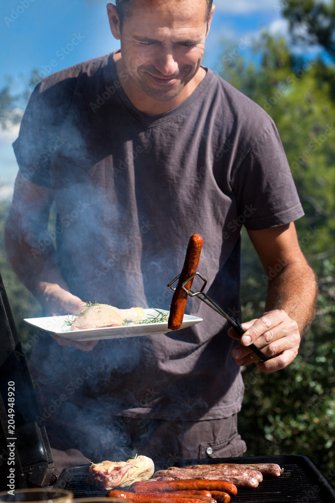 homme souriant qui fait griller des saucisses au barbecue Stock-foto |  Adobe Stock