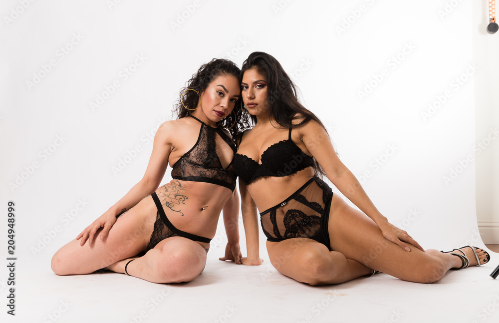 Attractive pale and tan hispanic women pose while sitting on a white background